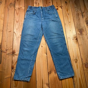 May include: A pair of medium-wash blue denim jeans featuring a high-waisted design with an elasticized waistband, a front zipper fly, and two side pockets. The jeans have a straight-leg cut and a classic five-pocket construction style.