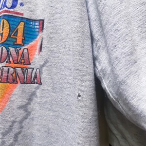 May include: Gray t-shirt with a colorful graphic print featuring the text "94" and "California".