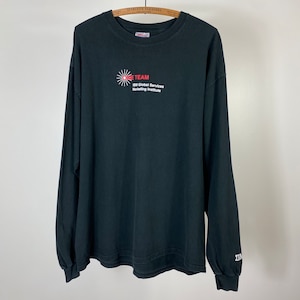 May include: Black long-sleeve shirt with the word "TEAM" in red and white text, along with "SM Global Services Marketing Institute." The shirt has a crew neck and long sleeves. The sleeve cuff has the letters "IMN" in white.