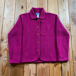 Puede incluir: Una chaqueta magenta de manga larga con botones, cuello clásico y acabado texturizado. La prenda cuenta con cinco botones magenta a juego en la parte delantera, un dobladillo curvo en la parte inferior y una etiqueta de marca en el cuello.