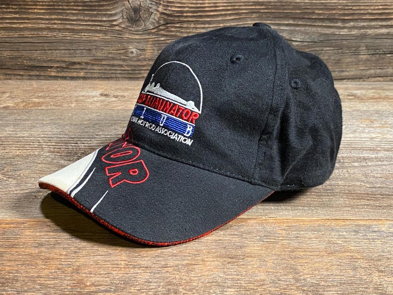 May include: Black baseball cap with the word "TERMINATOR" in red on the brim. The cap features a white and red design on the brim and the text "TERMINATOR IHB HOT ROD ASSOCIATION" in white, red, and blue.