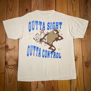 May include: White t-shirt featuring the Tasmanian Devil cartoon character. The shirt has the words "OUTTA SIGHT OUTTA CONTROL" in blue block letters. The cartoon character is brown, tan, and black.