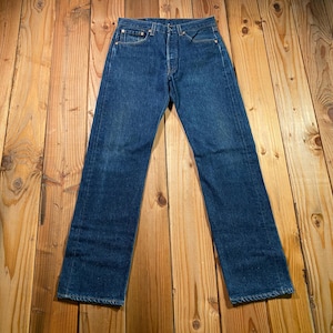May include: A pair of dark blue denim jeans featuring a classic five-pocket design, a button fly closure, and a straight-leg cut. The denim has a medium wash with subtle fading along the thighs and seams, finished with copper-toned metal rivets.