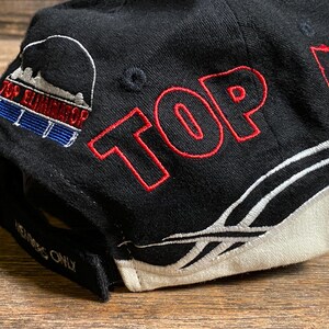 May include: Black baseball cap with red embroidered text "TOP ELITE" and a logo on the side. The cap features a white and black design with the Reebok logo. The text "MEMBERS ONLY" is embroidered on the brim.