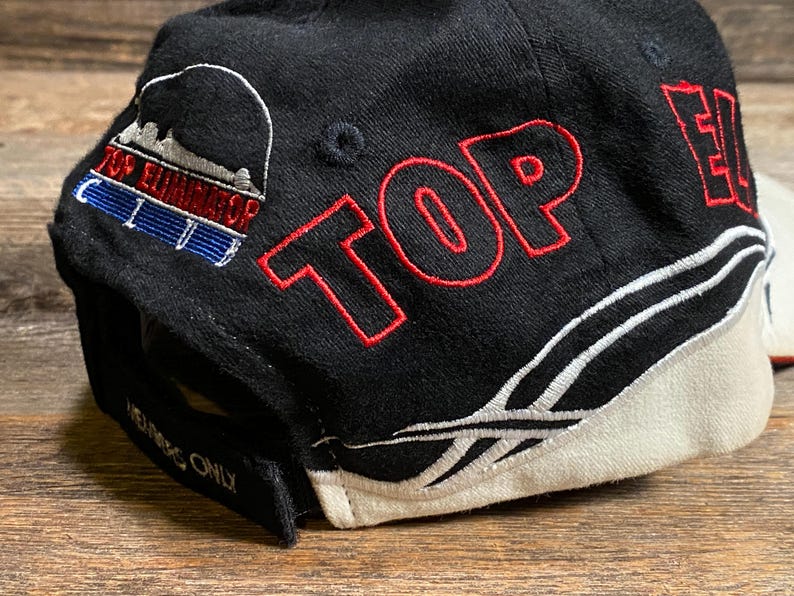 May include: Black baseball cap with red embroidered text "TOP ELITE" and a logo on the side. The cap features a white and black design with the Reebok logo. The text "MEMBERS ONLY" is embroidered on the brim.
