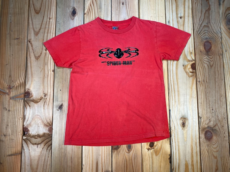 Op de afbeelding: Rood T-shirt met een zwarte spinnenafbeelding en de tekst "SPIDER-MAN". De korte mouwen tee heeft een ronde hals. Het shirt is gemaakt van een zacht materiaal en is geschikt voor vrijetijdskleding.