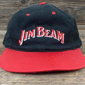 Puede incluir: Gorra de béisbol negra y roja con el logotipo de Jim Beam bordado en blanco y rojo. La gorra tiene una visera roja y una corona negra. La gorra está hecha de una tela duradera y tiene un ajuste clásico y estructurado.