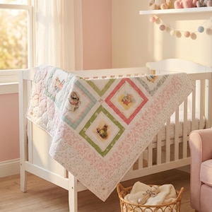 May include: A white baby quilt featuring a diamond-patterned design with illustrations of Peter Rabbit characters. The quilt has pastel-colored borders in pink, green, and blue, with a delicate dotted fabric trim and a soft, quilted texture throughout.