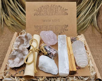 May include: A gift box with various crystals, a scroll, and a small glass bottle. The box is brown with the words "WITH LOVE" printed on it. The crystals include rose quartz, selenite, and a geode.