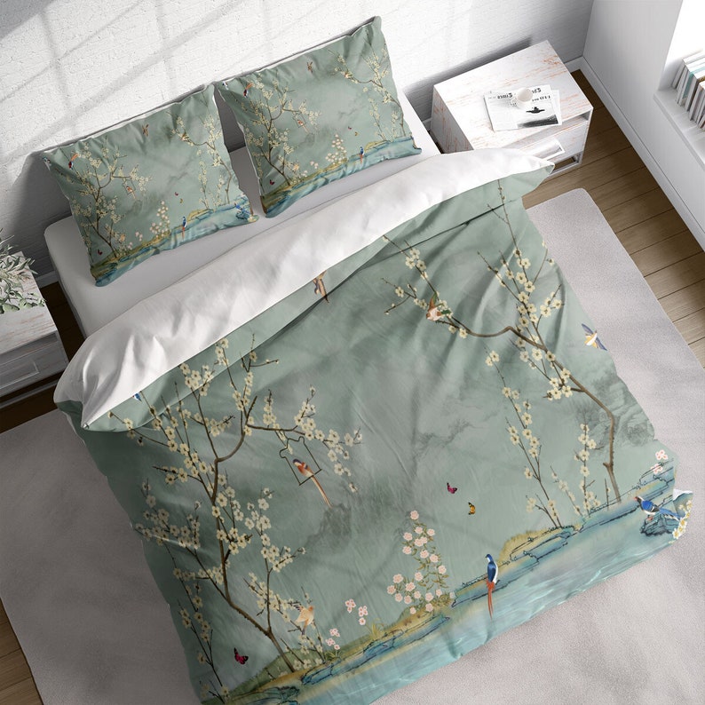 Puede incluir: Una funda n&oacute;rdica verde con un estampado floral con flores blancas, p&aacute;jaros y mariposas. La funda n&oacute;rdica tiene un fondo blanco y est&aacute; hecha de un tejido suave y transpirable.