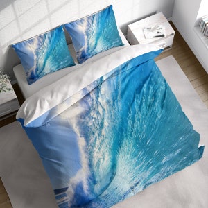 May include: A blue and white duvet cover with a large wave crashing on the front. The duvet cover is made of soft, comfortable fabric and features a realistic wave design.