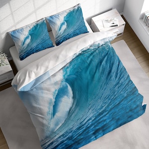 May include: A blue and white duvet cover featuring a large wave crashing on the ocean surface. The duvet cover is made from soft, comfortable fabric and has a realistic wave design.