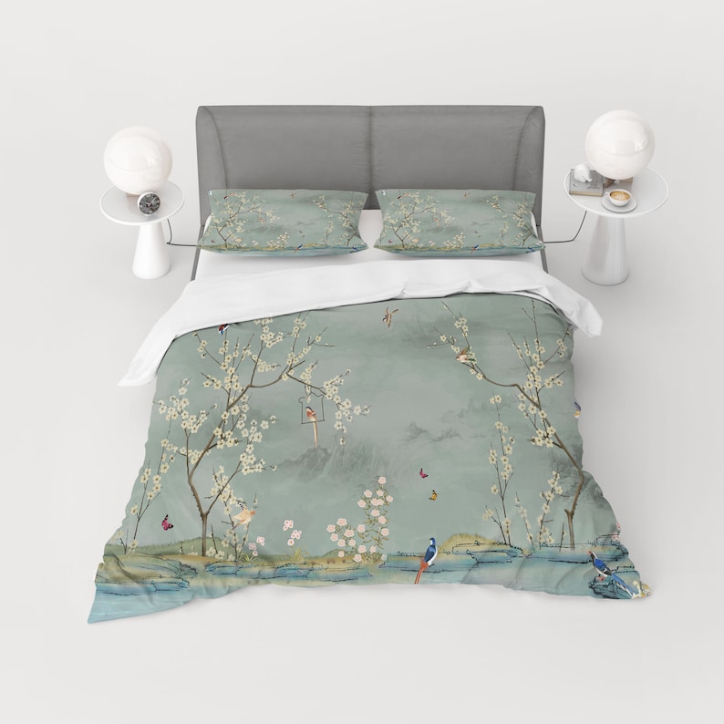 Puede incluir: Una funda n&oacute;rdica azul claro con un estampado floral con flores blancas, p&aacute;jaros y mariposas. La funda n&oacute;rdica est&aacute; en una cama con dos fundas de almohada a juego.