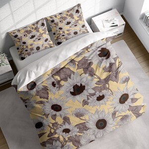 May include: A yellow duvet cover with a white and brown sunflower print. The duvet cover is on a bed with two matching pillowcases.