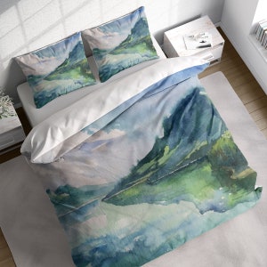 May include: A watercolor duvet cover featuring a mountain range reflected in a lake. The duvet cover is a soft blue and green with white clouds.