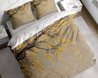 May include: A beige duvet cover with a pattern of a tree branch with yellow leaves. The duvet cover is on a bed with two matching pillowcases.