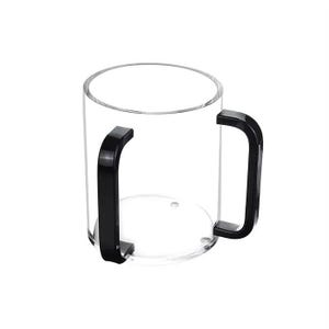 May include: A clear, cylindrical cup with two black, curved handles. The cup is transparent, allowing visibility of its contents. The handles are attached to the sides of the cup, providing a secure grip.