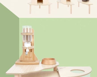 May include: A wooden hamster cage with three levels. The top level has a small house, the middle level has a water bottle and food bowl, and the bottom level has a house and a clear plastic container for sand.