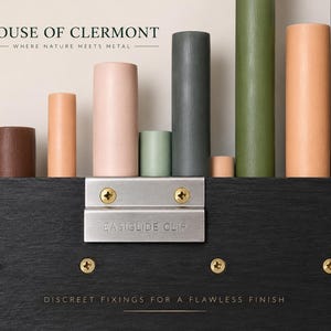 May include: A black wooden panel featuring a silver metal EASIGLIDE CLIP secured with two brass screws. Above the panel, a row of cylindrical pegs in various colors including brown, peach, pink, sage green, dark gray, and olive green are displayed.