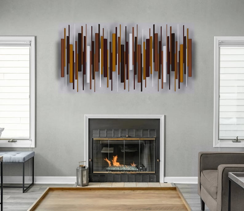 May include: A wall-mounted metal sculpture composed of numerous vertical rods of varying lengths and thicknesses. The rods are arranged in a horizontal pattern and feature a color palette of dark brown, copper, bronze, and white tones.