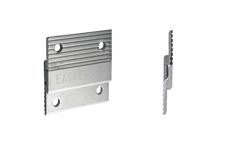 May include: A silver-colored metal wall mounting bracket with a ribbed top section and a smooth bottom section, featuring the embossed text EAGLE-CLIP. The bracket has four circular screw holes and is shown from both a front and a side profile view.