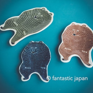 May include: Three ceramic bear-shaped dishes with a dotted pattern. The bears are standing upright with their arms raised. The dishes are in shades of green, brown, and black.