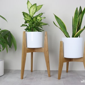 May include: Two white plant pots on wooden stands. The stands are made of white oak wood and have a simple, modern design. The pots are both white and cylindrical.