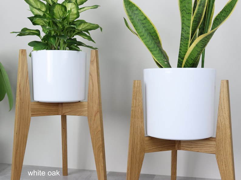 May include: Two white ceramic plant pots on wooden stands. The stands are made of white oak and have a simple, modern design. The pots are empty and ready to be filled with plants.