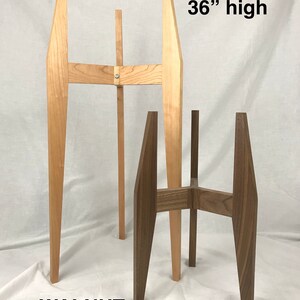 May include: Two plant stands, one made of maple wood and one made of walnut wood. The maple stand is 36 inches tall and the walnut stand is 18 inches tall.