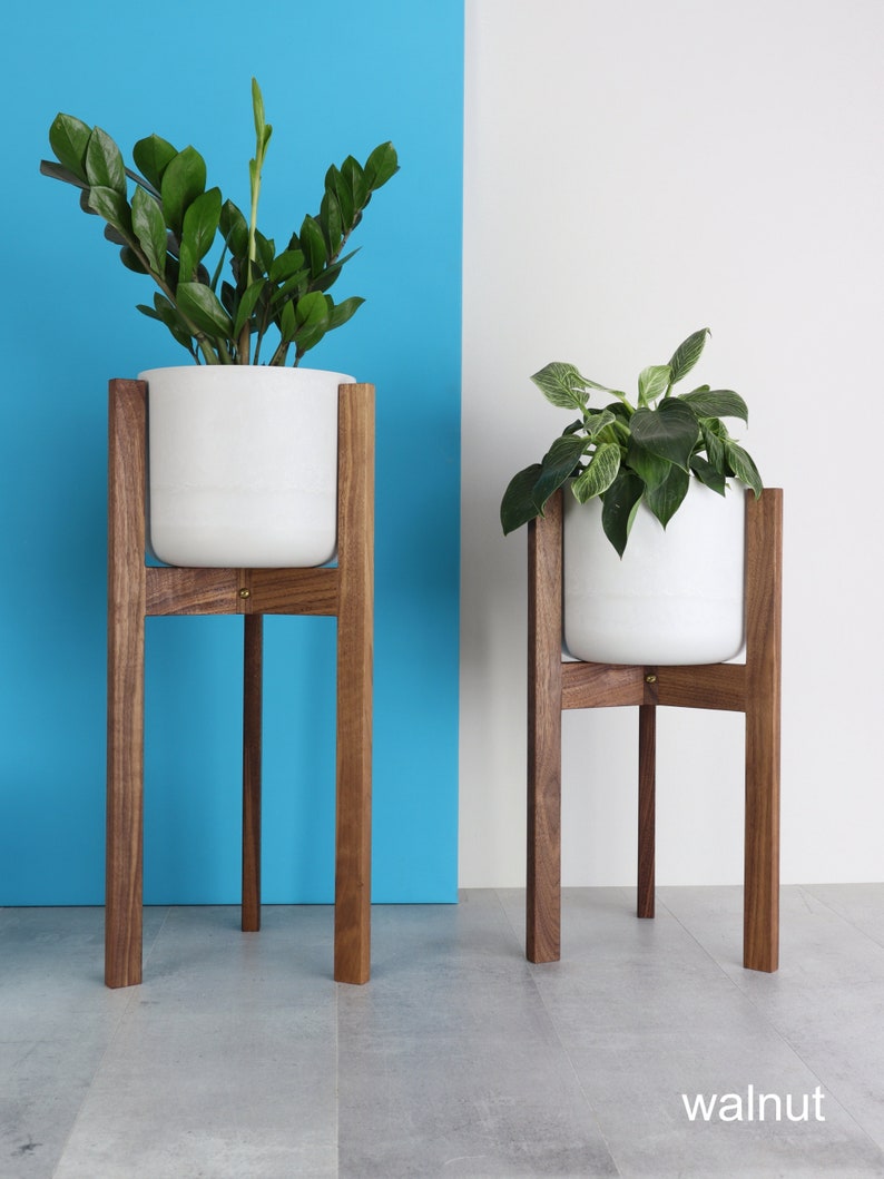 Puede incluir: Dos macetas de cer&aacute;mica blanca sobre soportes de madera. Los soportes son de madera de nogal y tienen un dise&ntilde;o simple y moderno. Las macetas est&aacute;n vac&iacute;as y listas para ser llenadas con plantas.