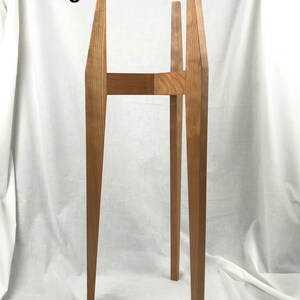 May include: A 30-inch tall plant stand made of cherry wood. The stand has a simple, modern design with four legs and a rectangular top.