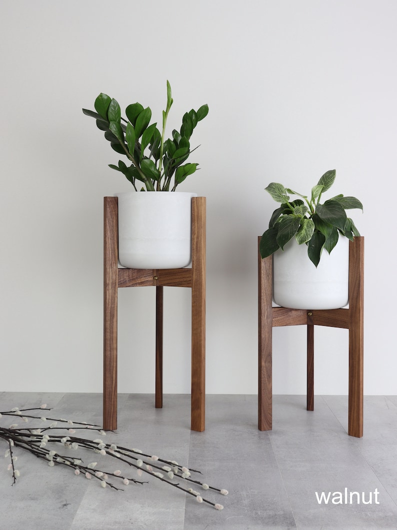 Puede incluir: Dos macetas de cer&aacute;mica blanca sobre soportes de madera. Los soportes son de madera de nogal y tienen un dise&ntilde;o simple y moderno. Las macetas est&aacute;n vac&iacute;as y listas para ser llenadas con plantas.