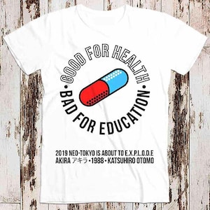 Peut inclure: T-shirt blanc avec un graphique circulaire noir représentant une pilule rouge et bleue avec le texte "GOOD FOR HEALTH - BAD FOR EDUCATION". Le texte "2019 NEO-TOKYO IS ABOUT TO E.X.P.L.O.D.E AKIRA アキラ・1988 KATSUHIRO OTOMO" est imprimé sous le cercle.