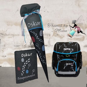 Könnte beinhalten: Ein schwarzer Schulranzen mit blau-weißem Design, das Lupen und Fußabdrücke zeigt. Der Rucksack hat den Text "ergobag" und "Die drei ? Kids" darauf. Ein schwarzer und grauer Schultüte mit blauen und roten Akzenten und dem Namen "Oskar" darauf. Ein schwarzer und grauer Ordner mit dem Namen "Oskar" und dem Text "Zeugnismappe" darauf. Der Text "Themil by Minec" ist im Hintergrund sichtbar.