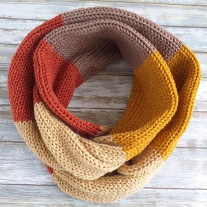 May include: A knitted infinity scarf in brown, orange, and yellow.