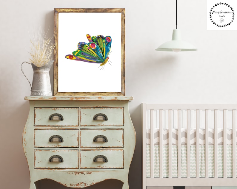 Op de afbeelding: Een kleurrijke vlinder met groene, blauwe, gele en rode vleugels is afgedrukt op een witte achtergrond. De print is ingelijst in een rustiek houten frame.