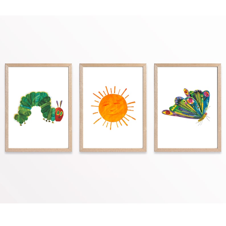 Op de afbeelding: Drie ingelijste prints met illustraties uit het kinderboek De Very Hungry Caterpillar. De eerste print toont een groene rups met rode ogen en poten. De tweede print toont een gele zon met een glimlachend gezicht. De derde print toont een kleurrijke vlinder met groene, blauwe en paarse vleugels.
