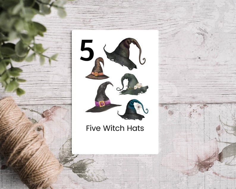 Puede incluir: Una tarjeta blanca con el n&uacute;mero 5 y el texto "Five Witch Hats" impreso en ella. Hay cinco sombreros de bruja ilustrados en la tarjeta. Los sombreros son de varios colores, incluyendo negro, verde y azul.