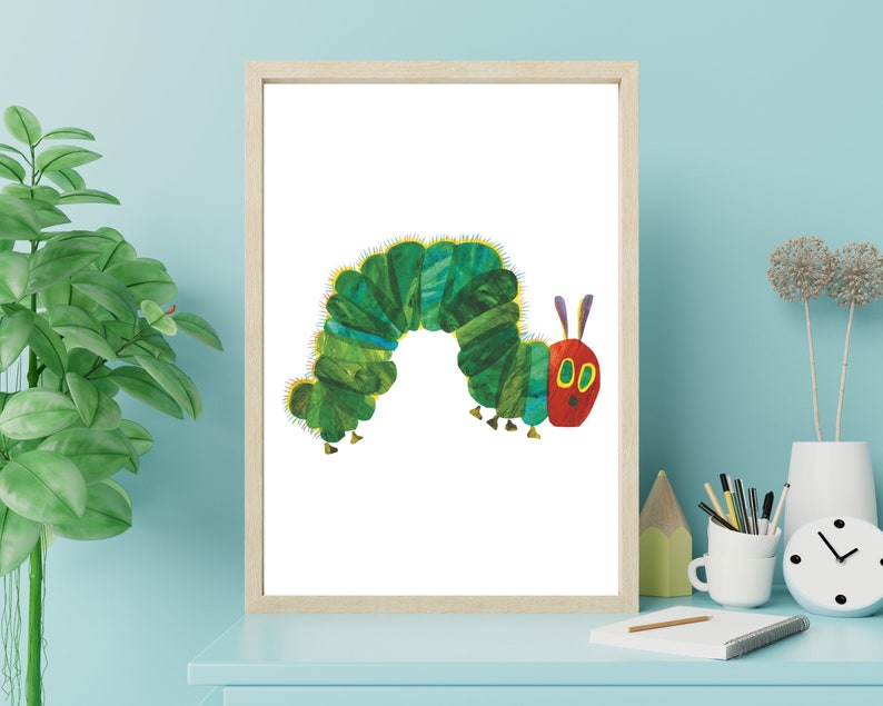Op de afbeelding: Een ingelijste print van een groene rups met een rood hoofd en gele ogen. De rups is in een cirkelvorm gekruld.