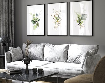 May include: Three framed watercolor prints of green and gold floral arrangements. The prints are hung on a gray wall above a white sofa.