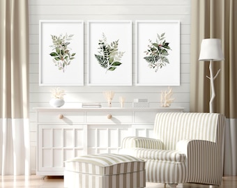 May include: Three framed botanical prints with watercolor illustrations of green leaves and ferns on a white background. The prints are hanging on a white shiplap wall above a white cabinet and a striped armchair with a matching ottoman.