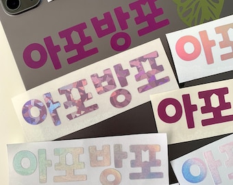 May include: A close-up of several stickers with the Korean word "아포방포" (apobangpo) written in different colours and styles. The stickers are on a grey surface with a butterfly sticker in the background.