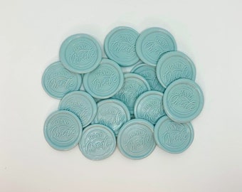 May include: A pile of light blue wax seals with the words "HAND MADE" embossed on each seal.