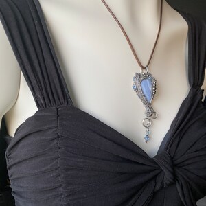 May include: A silver wire wrapped pendant featuring a blue agate stone with a brown leather cord necklace.