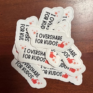 Può includere: Una collezione di adesivi bianchi fustellati con bordi ondulati, ognuno con il testo nero I OVERSHARE FOR KUDOS, un'icona rossa del pollice in su e piccoli accenti a forma di stella rossa sparsi attorno alle lettere, disposti in una pila.