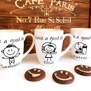 Puede incluir: Tres tazas de cerámica blanca con asas negras. Cada taza tiene una ilustración en blanco y negro de una persona y el texto "Have a good day". Las tazas están personalizadas con los nombres "Samuelo", "Elisa" y "Matteo".
