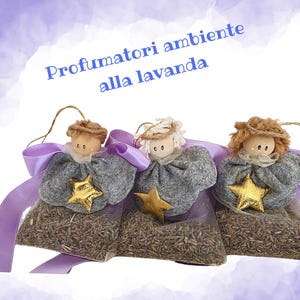 Könnte beinhalten: Drei Lavendelduft-Säckchen in Engelform. Jeder Engel hat einen grauen Körper, einen goldenen Stern und ein puppenartiges Gesicht. Sie sind mit einem lila Band gebunden. Der Text "Profumatori ambiente alla lavanda" ist sichtbar.