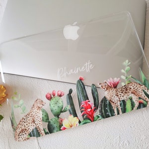 May include: Clear plastic laptop case with a desert-themed design. The case features a cheetah, cacti, and flowers in shades of green, pink, and yellow. The name "Phainette" is printed on the case.