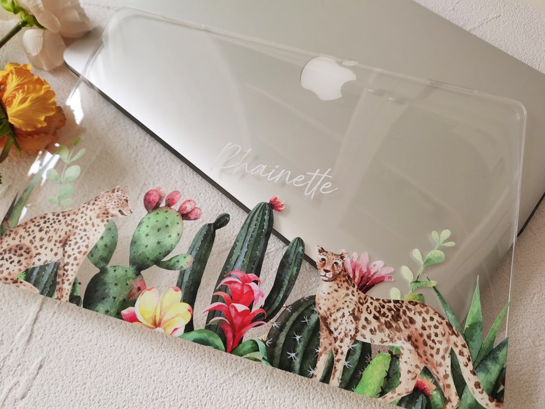 May include: Clear laptop case with a tropical design featuring two leopards, cacti, and flowers. The case is personalized with the name "Chainette" in white lettering.