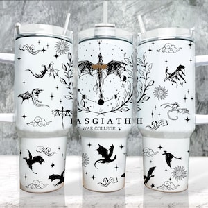 Puede incluir: Vaso térmico blanco con asa, con ilustraciones de dragones negros, elementos celestiales y el texto "IASGIATH WAR COLLEGE". El diseño incluye dragones, estrellas, nubes y soles. El vaso tiene una tapa blanca y una pajita reutilizable.